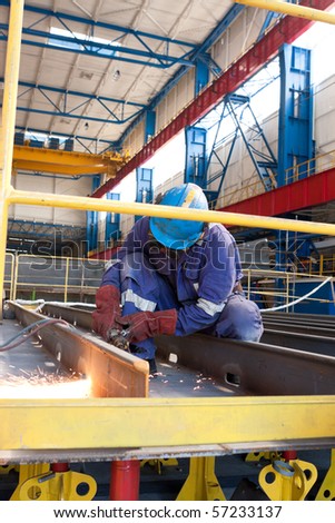 worker inside factory cut metal using blowtorch