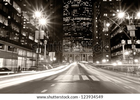 View of New York city at night with car\'s lights streaks passing by in a vintage-like shot with the Grand Central Terminal in the background.