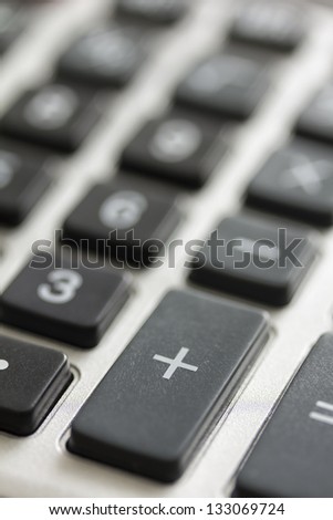 Calculator keyboard close-up shot with focus on the plus key symbolizing business and economy.