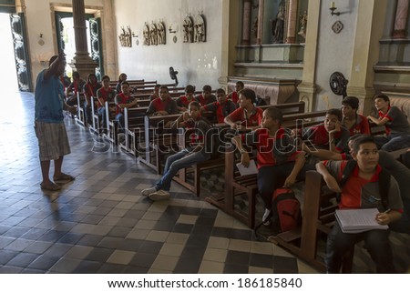OLINDA, BRAZIL - APRIL 7: Local students getting lectured by a tourism guide on the history and architecture of one of the historic Catholic churches of Olinda in Pernambuco, Brazil on April 7, 2014.