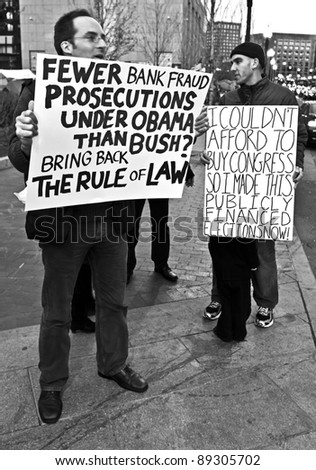 BOSTON, MASSACHUSETTS - NOVEMBER 19: Two members of the Occupy Boston protest holding signs by the South Station in Boston, Massachusetts, USA on November 19, 2011.