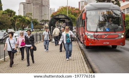 CURITIBA, BRAZIL - MARCH 20: Curitiba\'s public transportation system in Curitiba, Parana, Brazil with its red buses integrated to the bus stops loading and unloading passengers on March 20, 2014.