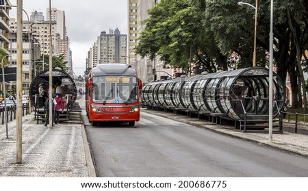 CURITIBA, BRAZIL - MARCH 30: Curitiba\'s public transportation system in Curitiba, PR, Brazil with its tube-shapped bus stops and red buses loading and unloading passengers on March 30, 2014.