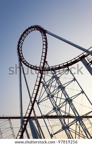 Loop of a scaring roller coaster back lit by the sunset.