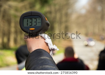 A police man hand pointing radar gun at speeding car.Concept: Crime,Speeding,traffic,surveillance