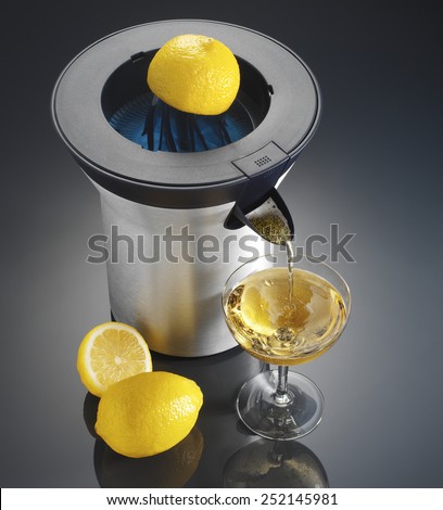 Lemon squeezer electrical with glass of Champagne and lemon on black background