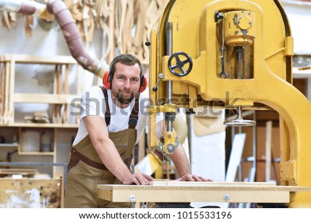portrait of a carpenter in work clothes and hearing protection in the workshop of a carpenter\'s shop