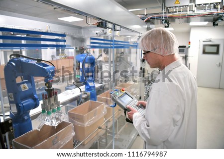 Conveyor belt worker operates a robot that transports insulin bags - modern factory for the production of medicines in the healthcare sector