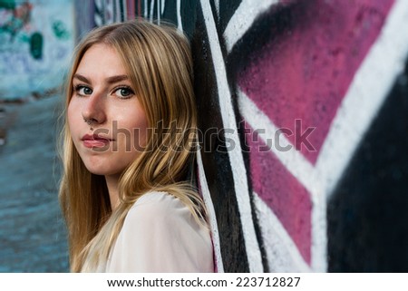 portrait of a young blonde girl with nose piercing and color graffiti background