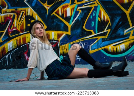 Blonde school girl sitting in front of graffiti wall