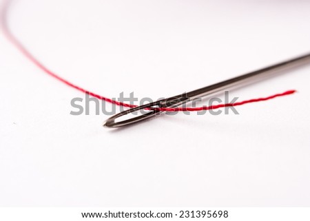 close up of a sewing needle head and red thread