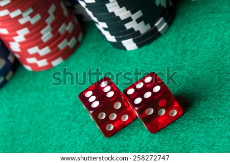 red casino dices and poker chips on green table