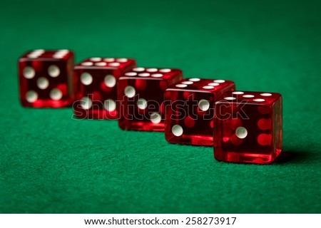 five red casino dices on a green table