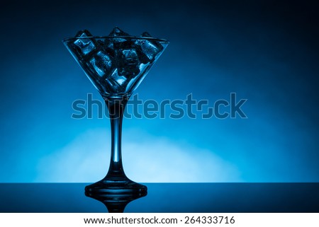 blue back lit martini glass filled with ice cubes