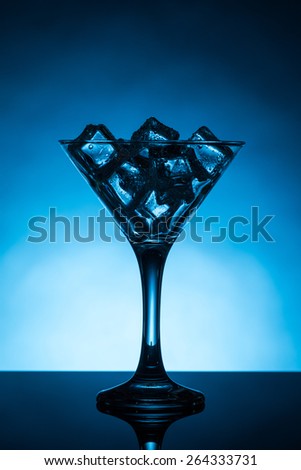 blue back lit martini glass filled with ice cubes