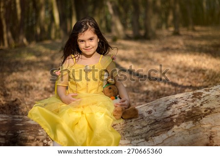 little girl in yellow princess dress in forest