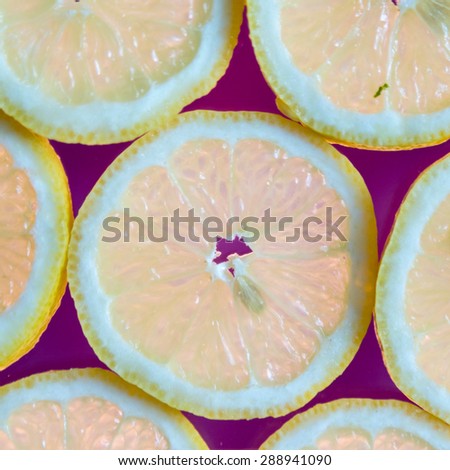 back lit fresh organic lemon slices on purple background