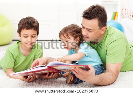 Kids reading story book with their father - sitting on the floor