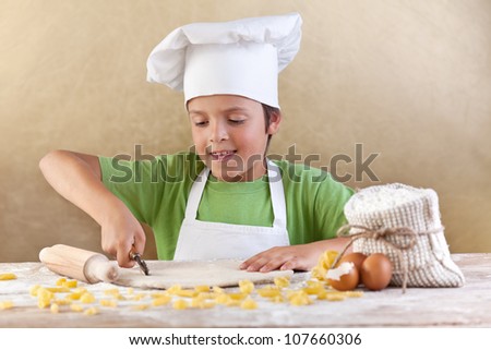 Little chef cutting the dough making pasta the traditional way