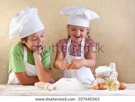 Kids preparing the dough for a cookie, pizza or pasta - having fun breaking the eggs
