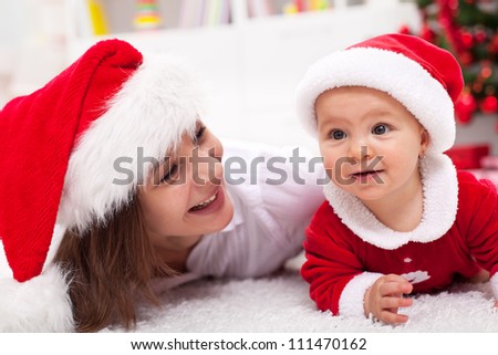 Our first Christmas - mother and baby with santa hats laying on the floor