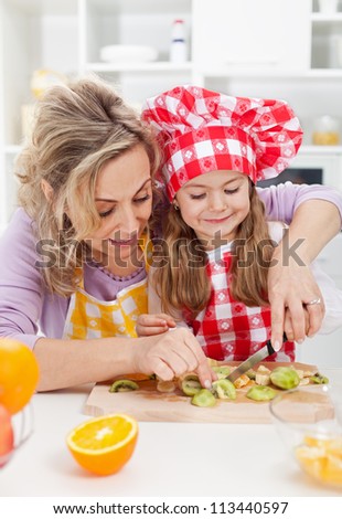 Woman and little girl making fresh fruits snack together - healthy eating concept