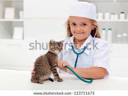 Little girl playing veterinary with her kitten - animal care concept