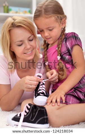 Mother teaching child how to tie shoes - showing the steps