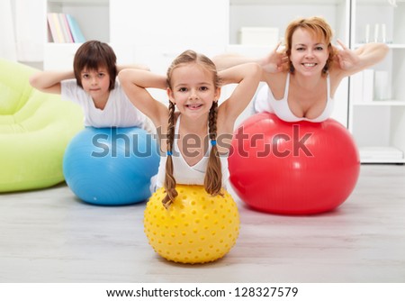 Kids and woman doing gymnastic at home - with large balls