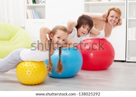 Happy healthy family exercising at home with large gymnastic balls