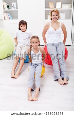 Woman and kids exercising at home using large gymnastic balls