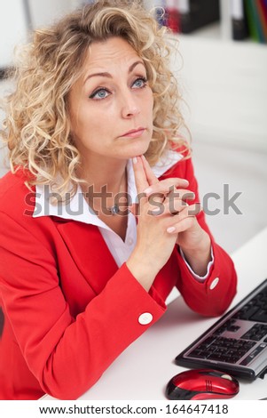 Business woman thinking at her desk propping her head - side view