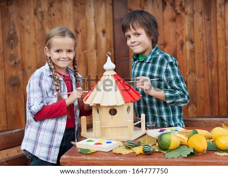 Kids painting the bird house preparing for winter - environmental awareness concept