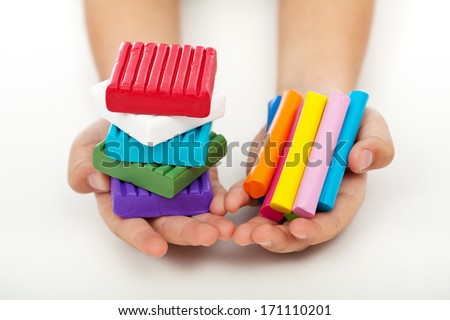Child hands holding colorful modeling clay bars and blocks