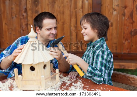 Smiling father and son building a wooden bird house together