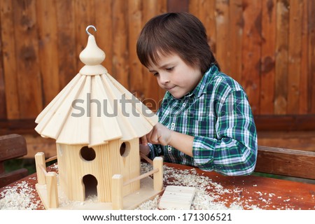 Little boy making the last finishing touches on a wooden bird house he is building
