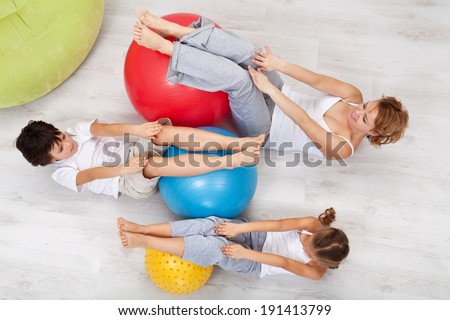 Woman and kids exercising together at home - with large gymnastic walls, top view