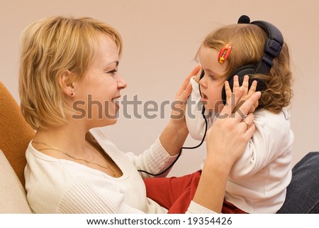 Woman and little girl singing and listening to music on large headset