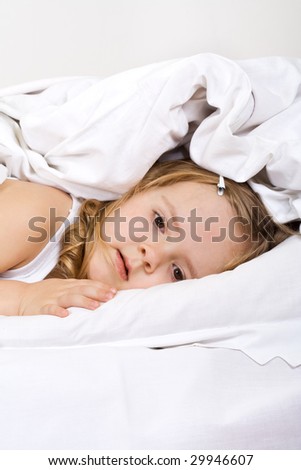 Little girl in bed under the blanket