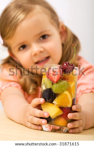 Happy little girl holding a summer fruits salad with bubbles