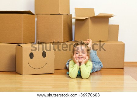 Little girl laying on the floor in front of cardboard boxes - moving concept