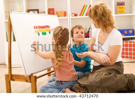 Preschool kids sitting on the floor doing math exercises with their mother