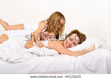 Happy morning - woman and kids in bed on a carefree morning