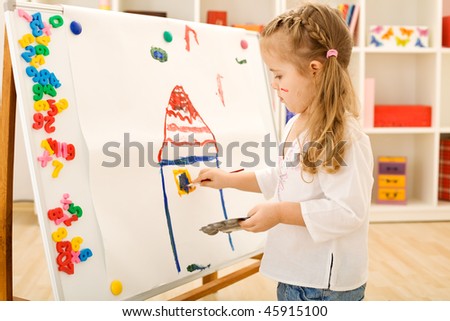 Little girl painting a colorful house on a large paper