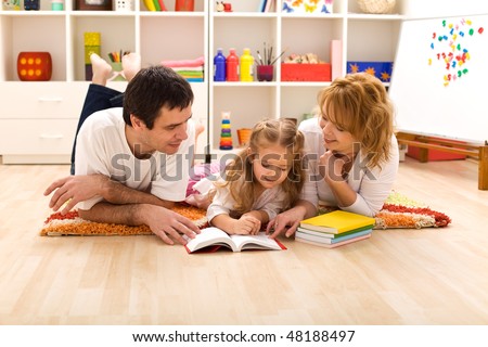 Happy family laying on the floor reading in the kids room