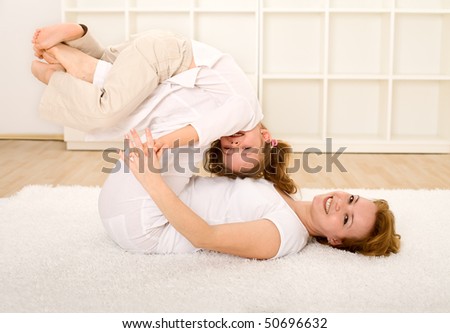 Woman and little girl having fun on the floor with exercises and wrestling