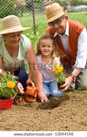 Grandparents teaching little girl the ways of gardening - planting flowers together