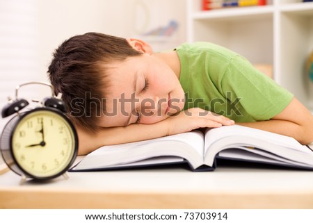 Boy fallen asleep on his book while studying late in the evening