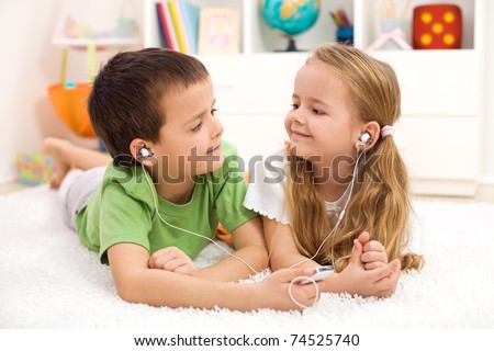 Kids sharing earphones listening to music laying on the floor