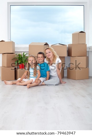 Happy family portrait in their new home sitting with cardboard boxes in front of window